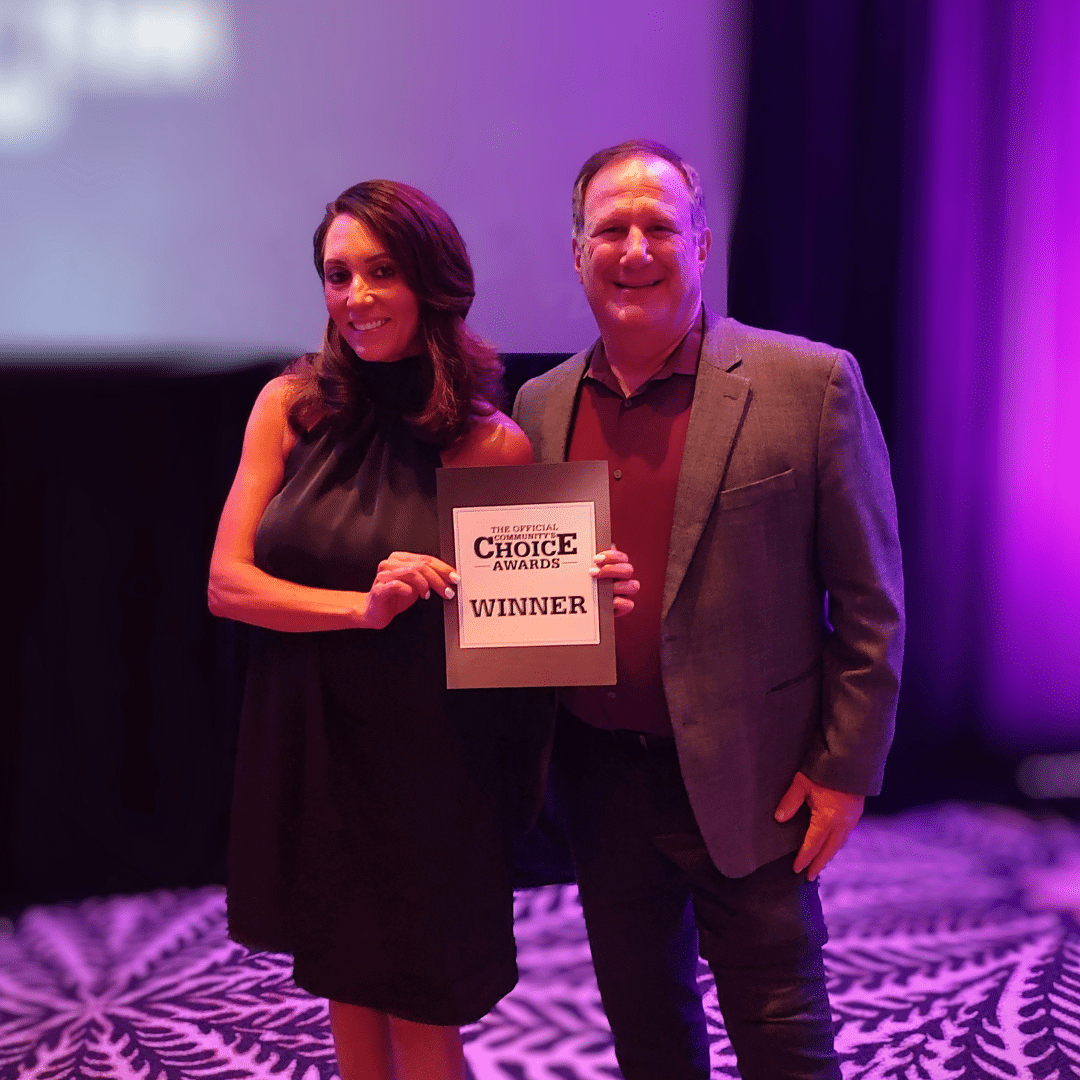 Two First Impression Ironworks employees posing with a sign that reads "Winner" at the Best of the Desert Awards ceremony